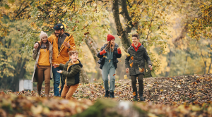 A family of five walking through an autumnal forest